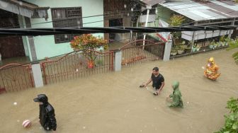 Sejumlah warga berjalan di kompleks perumahan yang terdampak banjir di Manado, Sulawesi Utara, Jumat (27/1/2023). [ANTARA FOTO/Adwit B Pramono].