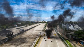 Gambar udara saat warga melakukan aksi menutup akses jalan menuju Gerbang Tol (GT) Jatikarya 1 dan 2, di ruas Jalan tol Cimanggis-Cibitung, Bekasi, Jawa Barat, Rabu (8/2/2023). [Suara.com/Alfian Winanto]