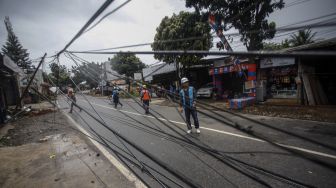 Sejumlah petugas mengevakuasi tiang listrik yang roboh di Jalan Raya Kalimulya, Cilodong, Depok, Jawa Barat, Kamis (9/2/2023). [ANTARA FOTO/Yulius Satria Wijaya].