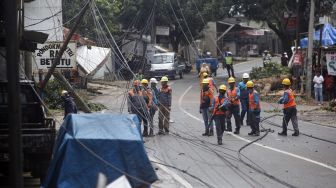 Sejumlah petugas mengevakuasi tiang listrik yang roboh di Jalan Raya Kalimulya, Cilodong, Depok, Jawa Barat, Kamis (9/2/2023). [ANTARA FOTO/Yulius Satria Wijaya].