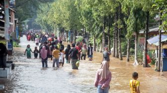 Warga melintasi banjir di Desa Kedawung, Grati, Pasuruan, Jawa Timur, Sabtu (11/2/2023). [ANTARA FOTO/Umarul Faruq].