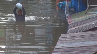 Warga membawa barang dari rumahnya yang terendam banjir di Pucang Sawit, Solo, Jawa Tengah, Jumat (17/2/2023).  [ANTARAFOTO/Maulana Surya].