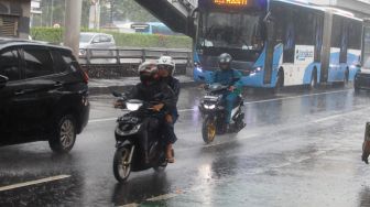 Pengendara motor nelintas saat hujan lebat di Jalan Gatot Subroto, Jakarta, Kamis (3/3/2023). [Suara.com/Alfian Winanto]