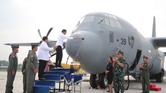 Presiden Joko Widodo atau Jokowi menyiramkan air bunga ke badan pesawat C-130J-30 Super Hercules yang diserahkan ke Panglima TNI. [Kemnhan]
