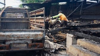 Petugas membersihkan sisa-sisa kebakaran di tempat penampungan hewan di Duren Sawit, Jakarta Timur, Senin (27/3/2023). [Suara.com/Alfian Winanto]