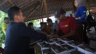 Petugas bank BRI melayani warga saat proses pembayaran makam yang terkena pembangunan jalan tol Solo-Jogja di Kateguhan, Sawit, Boyolali, Jawa Tengah, Jumat (31/3/2023). [ANTARA FOTO/Aloysius Jarot Nugroho].