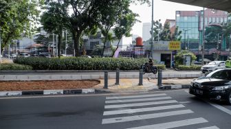 Kendaraan melintas di trotoar yang telah berubah fungsi menjadi jalan raya di Simpang Santa, Jakarta Selatan, Selasa (18/4/2023). [Suara.com/Alfian Winanto]