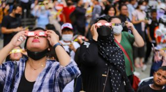 Warga mengamati fenomena Gerhana Matahari Hibrida di Taman Ismail Marzuki (TIM), Jakarta Pusat, Kamis (20/4/2023). [Suara.com/Alfian Winanto]