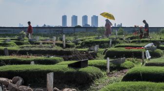 Warga melakukan ziarah kubur di Tempat Pemakaman Khusus Covid-19 TPU Rorotan, Jakarta Utara, Sabtu (22/4/2023). [Suara.com/Alfian Winanto]