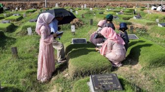 Warga berdoa saat melakukan ziarah kubur di Tempat Pemakaman Khusus Covid-19 TPU Rorotan, Jakarta Utara, Sabtu (22/4/2023). [Suara.com/Alfian Winanto]