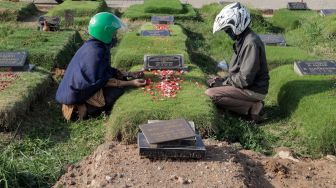 Warga berdoa saat melakukan ziarah kubur di Tempat Pemakaman Khusus Covid-19 TPU Rorotan, Jakarta Utara, Sabtu (22/4/2023). [Suara.com/Alfian Winanto]