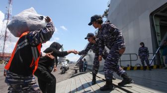 Personel TNI AL membantu pemudik masuk ke KRI Banjarmasin-592 di Koarmada II, Surabaya, Jawa Timur, Selasa (25/4/2023). [ANTARA FOTO/Didik Suhartono]