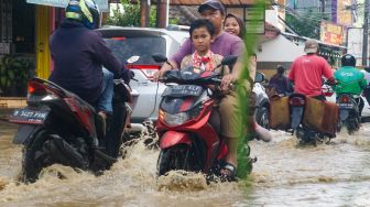 Warga melintasi banjir yang menggenangi Pondok Gede Permai, Bekasi, Jawa Barat, Kamis (4/5/2023). [Suara.com/Alfian Winanto]