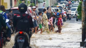 Warga melintasi banjir yang menggenangi Pondok Gede Permai, Bekasi, Jawa Barat, Kamis (4/5/2023). [Suara.com/Alfian Winanto]