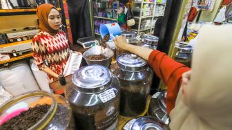 Pedagang memasukkan kopi ke dalam kemasan untuk pembeli di Dunia Kopi, Pasar Santa, Jakarta Selatan, Jumat (5/5/2023). [Suara.com/Alfian Winanto]