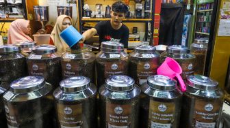 Pedagang memasukkan kopi ke dalam kemasan untuk pembeli di Dunia Kopi, Pasar Santa, Jakarta Selatan, Jumat (5/5/2023). [Suara.com/Alfian Winanto]