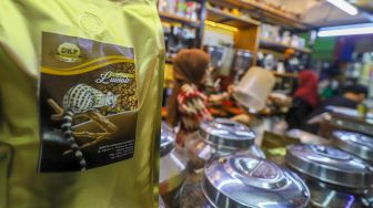 Pedagang memasukkan kopi ke dalam kemasan untuk pembeli di Dunia Kopi, Pasar Santa, Jakarta Selatan, Jumat (5/5/2023). [Suara.com/Alfian Winanto]