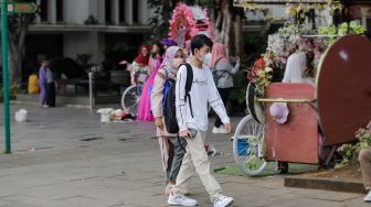 Pengunjung memakai masker saat berwisata di Kawasan Kota Tua, Jakarta Barat, Sabtu (6/5/2023). [Suara.com/Alfian Winanto]