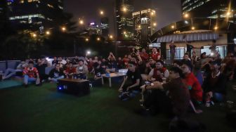 Sejumlah warga menyaksikan pertandingan final cabang olahraga sepak bola antara Indonesia melawan Thailand di Green Cafe Semanggi, Jakarta, Selasa (16/5/2023). [Suara.com/Alfian Winanto]