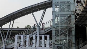 Pekerja menyelesaikan proyek pembangunan Jembatan Penyebrangan Orang (JPO) Stasiun Klender Baru di Kelnder, Jakarta Timur, Selasa (16/5/2023). [Suara.com/Alfian Winanto]