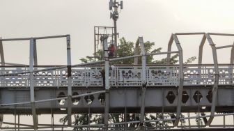 Pekerja menyelesaikan proyek pembangunan Jembatan Penyebrangan Orang (JPO) Stasiun Klender Baru di Kelnder, Jakarta Timur, Selasa (16/5/2023). [Suara.com/Alfian Winanto]