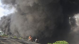 Dua warga menyaksikan kebakaran pabrik plastik di Kalideres, Jakarta Barat, Jumat (19/5/2023).  [ANTARA FOTO/Fauzan].