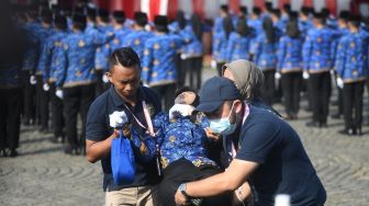 Petugas menolong peserta yang pingsan saat upacara peringatan hari lahir Pancasila di Monas, Jakarta, Kamis (1/6/2023).  [ANTARA FOTO/Akbar Nugroho Gumay].