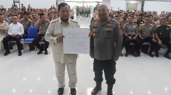 Menteri Pertahanan Prabowo Subianto (kiri) ditemani Kepala Sespim Polri Irjen Pol Chryshnanda (kanan) menunjukkan plakat berisi pesan untuk Polri saat mengisi acara Dialog Kebangsaan di Sespim Lemdiklat Polri, Bandung, Jawa Barat, Jumat (16/6/2023). [Suara.com/Alfian Winanto]