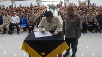 Menteri Pertahanan Prabowo Subianto (tengah) ditemani Kepala Sespim Polri Irjen Pol Chryshnanda (kanan) menuliskan plakat berisi pesan untuk Polri saat mengisi acara Dialog Kebangsaan di Sespim Lemdiklat Polri, Bandung, Jawa Barat, Jumat (16/6/2023). [Suara.com/Alfian Winanto]