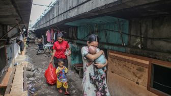 Sejumlah warga berjalan di kawasan permukiman di bawah jalan tol dalam kota Cawang-Tomang-Pluit di Jelambar Baru, Jakarta Barat, Selasa (20/6/2023). [ANTARA FOTO/Fauzan].