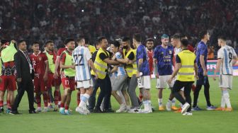 Seorang suporter mengenakan jersey Timnas Indonesia dan Argentina diamankan usai masuk ke dalam lapangan Stadion Utama Gelora Bung Karno (SUGBK), Senayan, Jakarta, Senin (19/6/2023). [Suara.com/Dwi Bowo Raharjo]