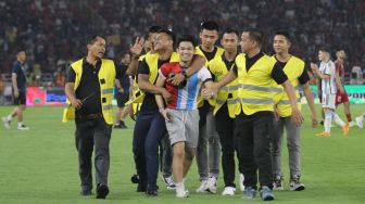 Seorang suporter mengenakan jersey Timnas Indonesia dan Argentina diamankan usai masuk ke dalam lapangan Stadion Utama Gelora Bung Karno (SUGBK), Senayan, Jakarta, Senin (19/6/2023). [Suara.com/Dwi Bowo Raharjo]