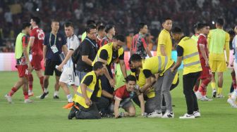 Seorang suporter mengenakan jersey Timnas Indonesia dan Argentina diamankan usai masuk ke dalam lapangan Stadion Utama Gelora Bung Karno (SUGBK), Senayan, Jakarta, Senin (19/6/2023). [Suara.com/Dwi Bowo Raharjo]