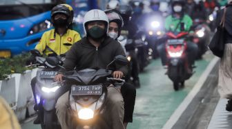 Pemotor memakai masker saat melintas di Kawasan Bundaran HI, Jakarta, Rabu (21/6/2023). [Suara.com/Alfian Winanto]