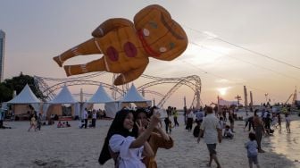 Warga berswafoto dengan layang-layang saat Festival Layang-layang Jakarta di Pantai Lagoon Ancol, Kamis (22/6/2023). [Suara.com/Alfian Winanto]