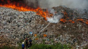 Petugas berusaha memadamkan api saat kebakaran lahan di Tempat Pembuangan Akhir (TPA) Desa Dermasuci, Kabupaten Tegal, Jawa Tengah, Selasa (27/6/2023). [ANTARA FOTO/Oky Lukmansyah].