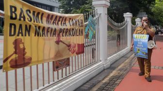 Kepala Desa Tiberias, Abner Patras saat menggelar aksi demo tunggal di depan Gedung Mahkamah Agung RI, Jakarta Pusat, Rabu (5/7/2023). [Suara.com/Alfian Winanto]