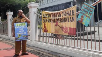 Kepala Desa Tiberias, Abner Patras saat menggelar aksi demo tunggal di depan Gedung Mahkamah Agung RI, Jakarta Pusat, Rabu (5/7/2023). [Suara.com/Alfian Winanto]