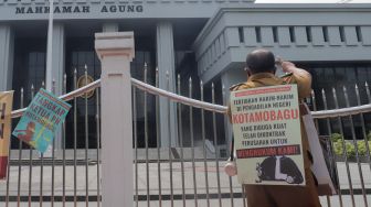 Kepala Desa Tiberias, Abner Patras saat menggelar aksi demo tunggal di depan Gedung Mahkamah Agung RI, Jakarta Pusat, Rabu (5/7/2023). [Suara.com/Alfian Winanto]