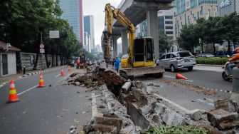 Pekerja membongkar pembatas Jalan HR Rasuna Said di Kuningan, Jakarta, Jumat (7/7/2023). [Suara.com/Alfian Winanto]

