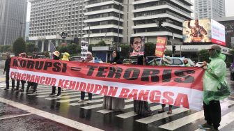 Puluhan emak-emak yang mengatasnamakan Aliansi Rakyat Menggugat membentangkan poster saat menggelar aksi kritik Presiden Jokowi di persimpangan Sarinah, Jalan MH Thamrin Jakarta Pusat, Jumat (7/7/2023). [Suara.com/Dea]