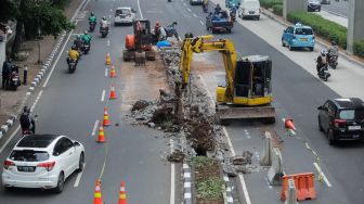 Pekerja membongkar pembatas Jalan HR Rasuna Said di Kuningan, Jakarta, Jumat (7/7/2023). [Suara.com/Alfian Winanto]
