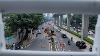 Pekerja membongkar pembatas Jalan HR Rasuna Said di Kuningan, Jakarta, Jumat (7/7/2023). [Suara.com/Alfian Winanto]
