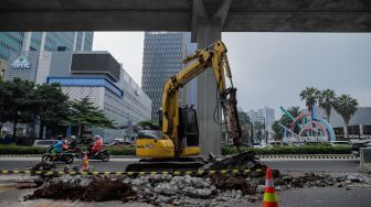 Pekerja membongkar pembatas Jalan HR Rasuna Said di Kuningan, Jakarta, Jumat (7/7/2023). [Suara.com/Alfian Winanto]

