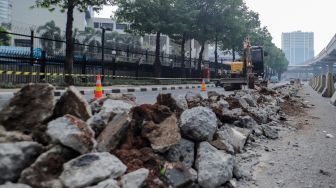 Pekerja membongkar pembatas Jalan HR Rasuna Said di Kuningan, Jakarta, Jumat (7/7/2023). [Suara.com/Alfian Winanto]
