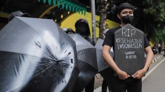 Sejumlah massa saat menggelar aksi unjuk rasa 'Payung Duka' di depan Kementerian Kesehatan, Jakarta, Jumat (14/7/2023). [Suara.com/Alfian Winanto]