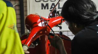 Pekerja mengkonversi vespa klasik menjadi vespa listrik di bengkel Elders Garage, Gedung Smesco Jakarta, Kamis (28/7/2022). [Suara.com/Alfian Winanto]