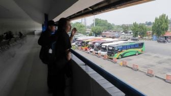 Sejumlah calon penumpang melihat bus dari loket lantai dua Terminal Kampung Rambutan, Jakarta Timur, Kamis (20/7/2023). [Suara.com/Alfian Winanto]
