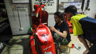 Pekerja mengkonversi vespa klasik menjadi vespa listrik di bengkel Elders Garage, Gedung Smesco Jakarta, Kamis (28/7/2022). [Suara.com/Alfian Winanto]