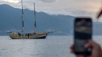 Warga mengabadikan kapal Arka Kinari yang membuang sauh di Pantai Mamboro, Teluk Palu, Palu, Sulawesi Tengah, Sabtu (22/7/2023). [ANTARA FOTO/Basri Marzuki/Spt]